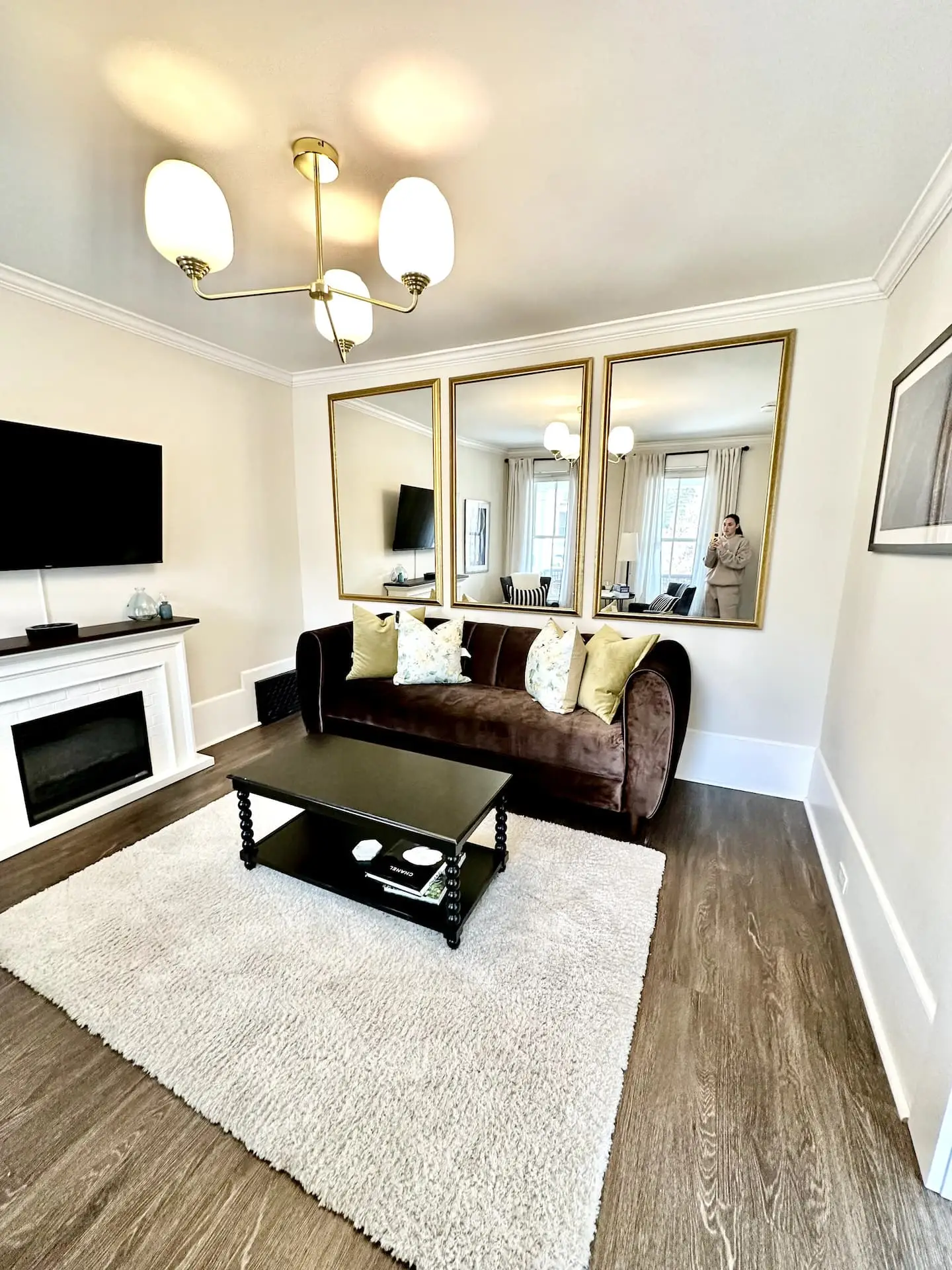 A moody living room with a dark sofa, fireplace, and mirrors